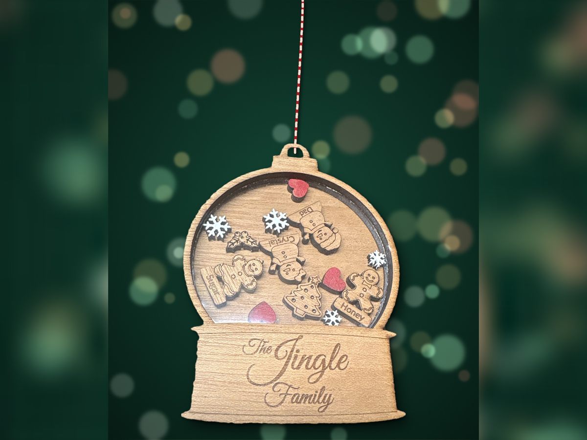 Wooden snow globe ornament engraved 'The Jingle Family', with named gingerbread and snowman pieces behind a clear window